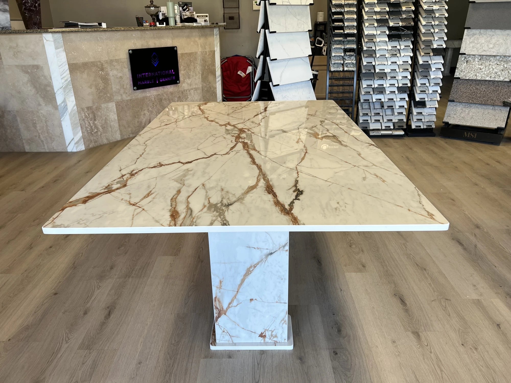 Dekton Awake dining table with book-matched white marble-look veining and square pedestal base — premium dekton surfaces fabricated and installed by Signatur...
