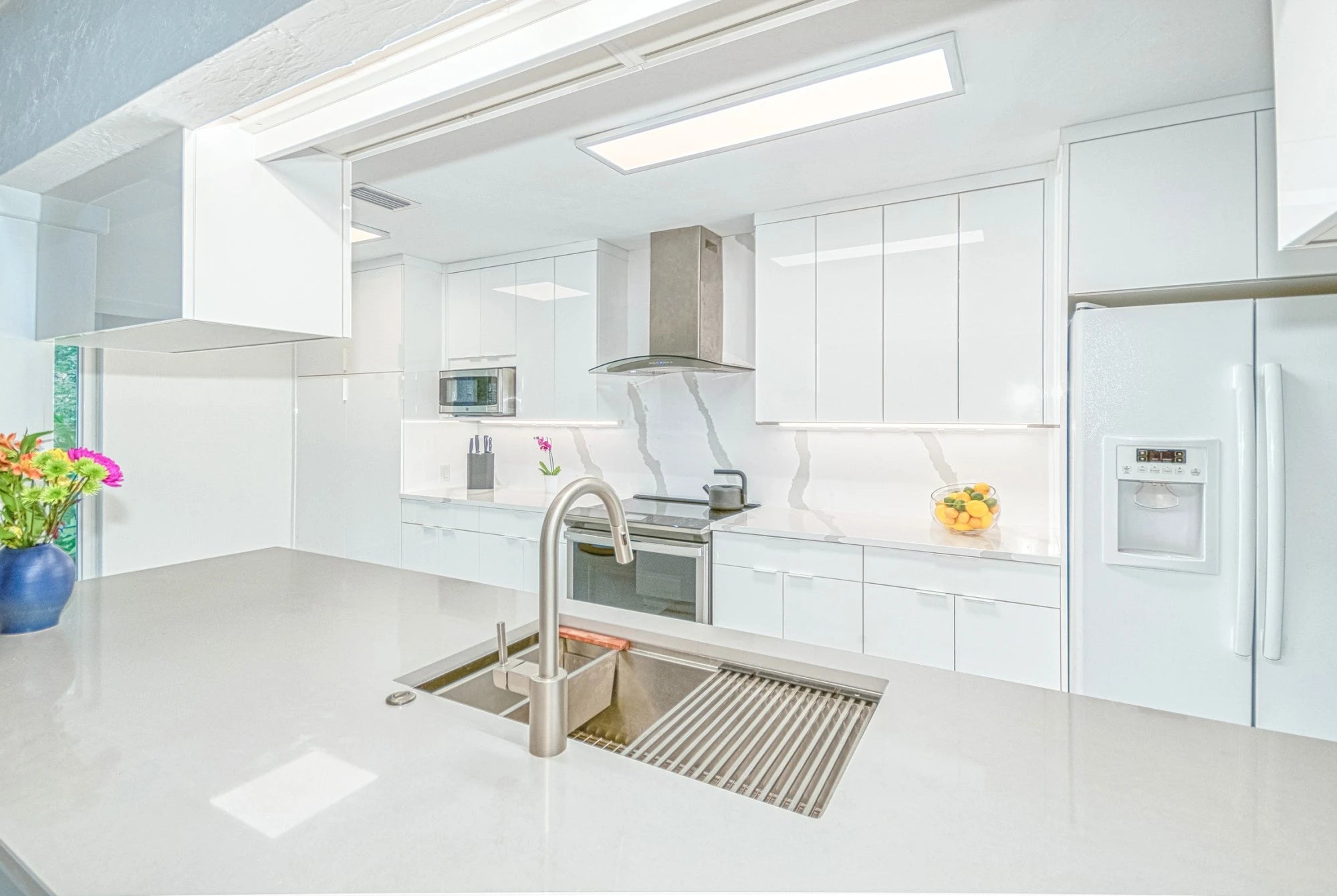 Silestone Bianco Calacatta kitchen island with white veined finish and waterfall edge — engineered quartz countertops fabricated and installed by Signature S...