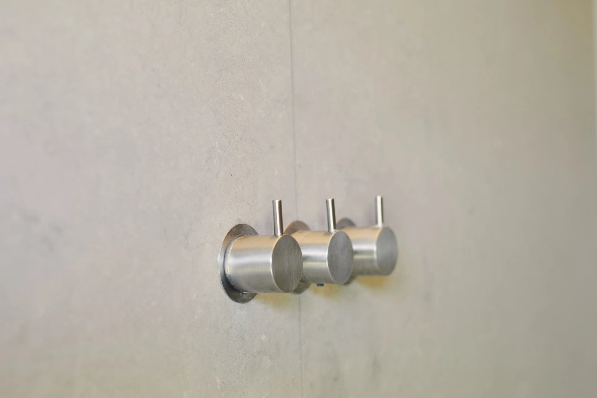 Silestone Coral Clay shower wall with brushed stainless steel fixtures and warm beige finish — engineered quartz countertops fabricated and installed by Sign...