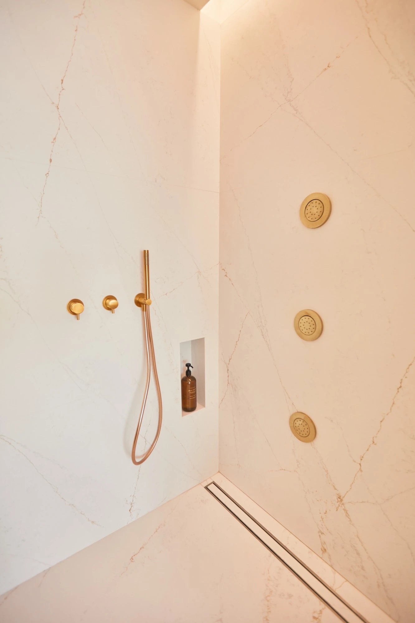 Silestone Ethereal Glow shower walls with warm veining and gold fixtures — premium quartz countertops installed by Signature Stone Las Vegas