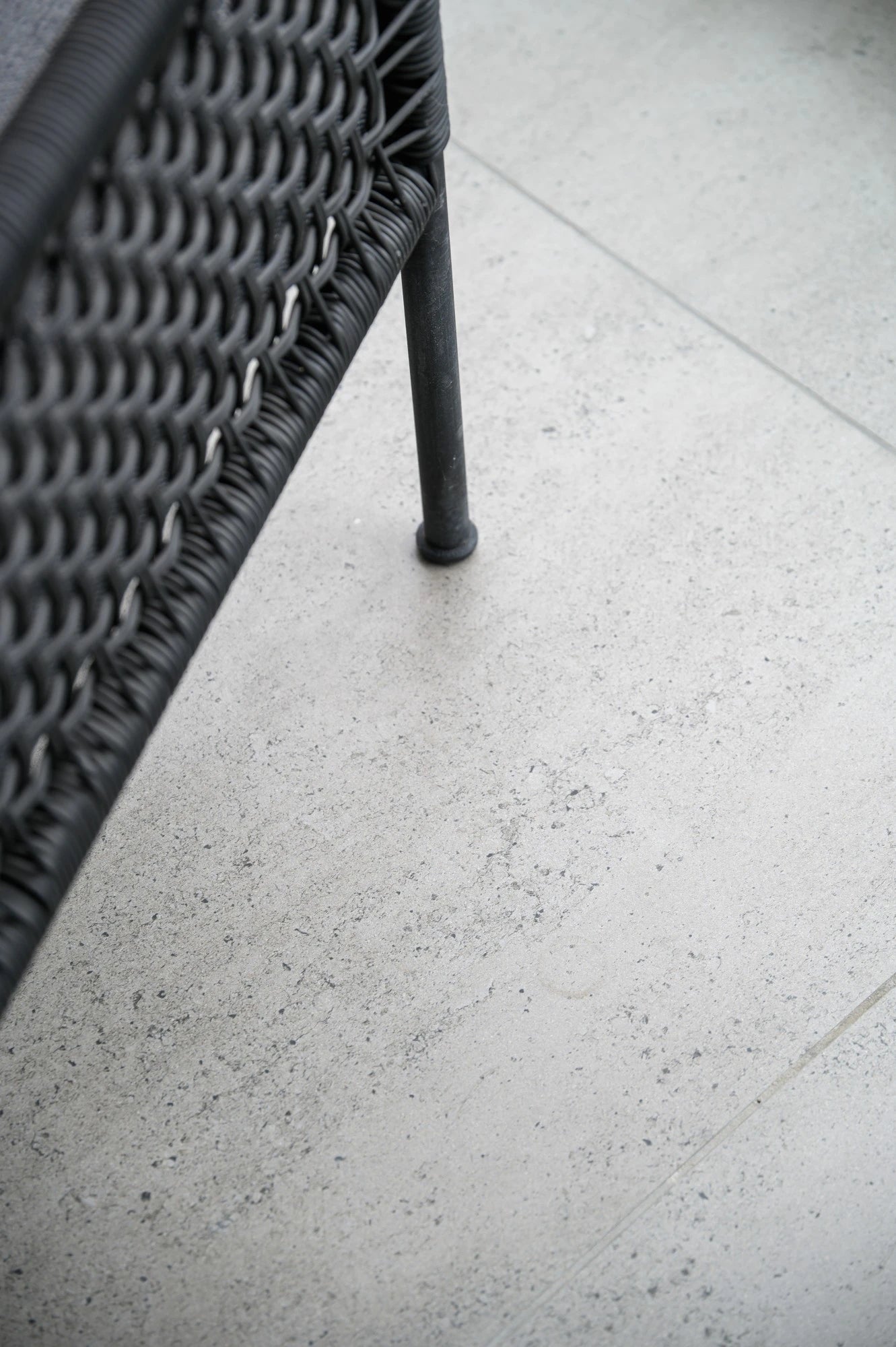 Dekton Keon flooring with light speckled finish and black furniture leg — premium dekton surfaces fabricated and installed by Signature Stone LV