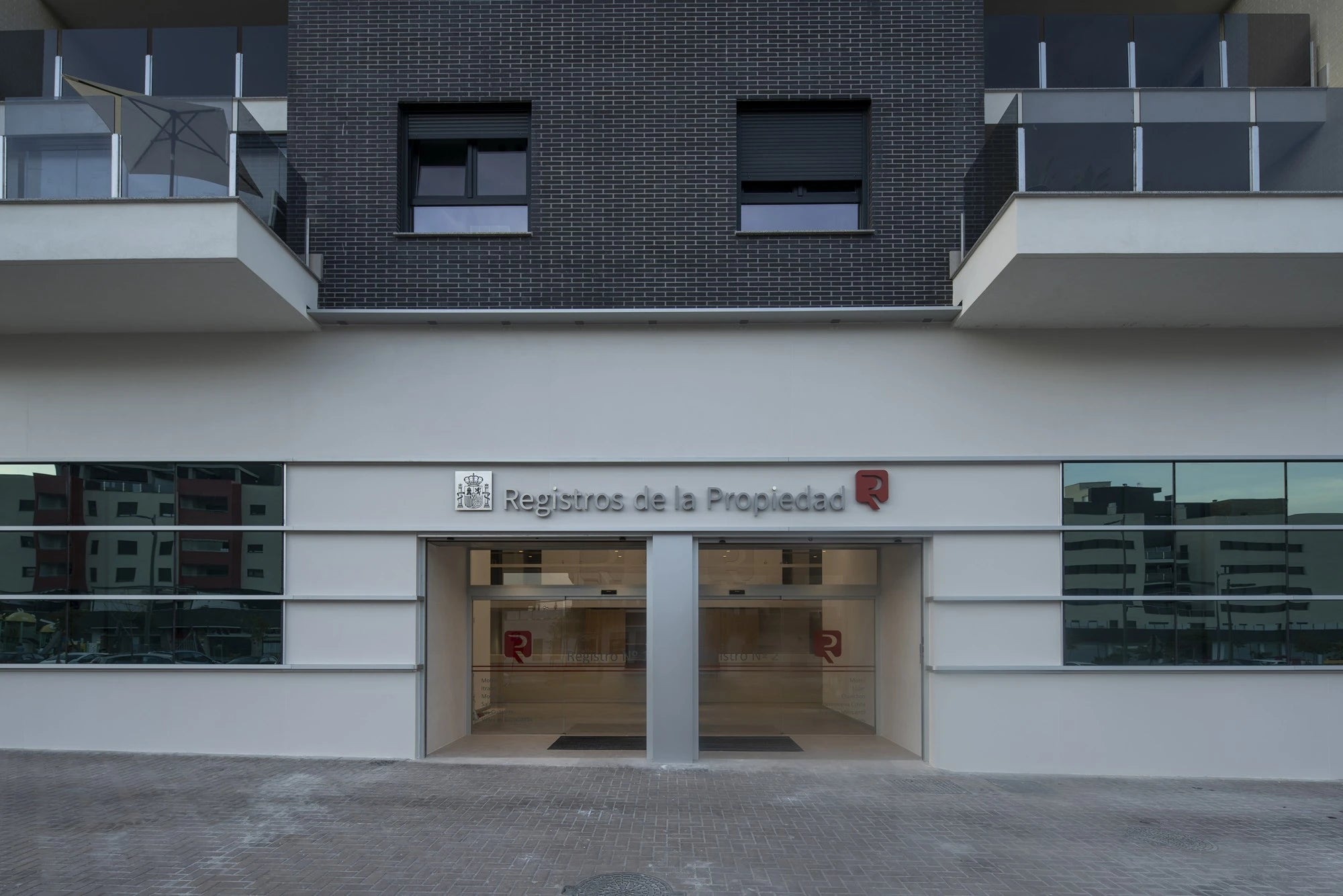 Dekton Moone commercial building facade with dark brick upper level and white concrete lower section — premium dekton surfaces fabricated and installed by Si...
