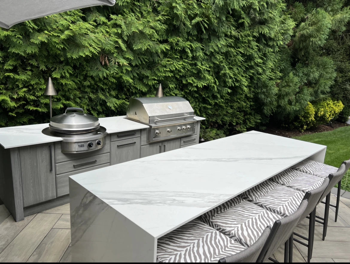 Dekton Olimpo outdoor kitchen island with white marble-look finish and waterfall edge — premium dekton surfaces fabricated and installed by Signature Stone LV
