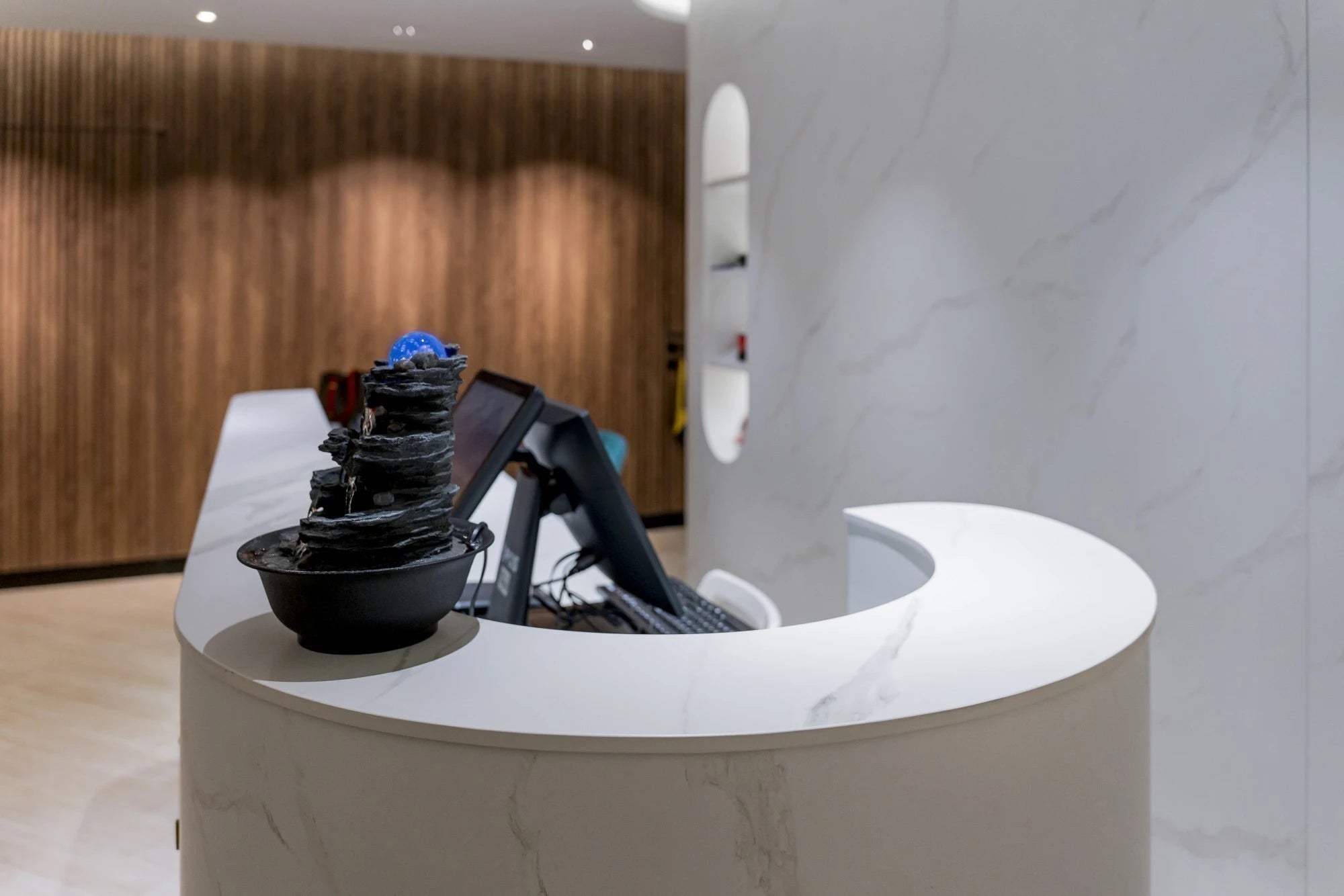 Dekton Opera curved reception desk with white marble-look finish and waterfall edge — premium dekton surfaces fabricated and installed by Signature Stone LV