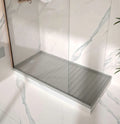 Silestone quartz shower tray with gray finish and glass enclosure in marble-walled bathroom — quartz countertops installed by Signature Stone Las Vegas