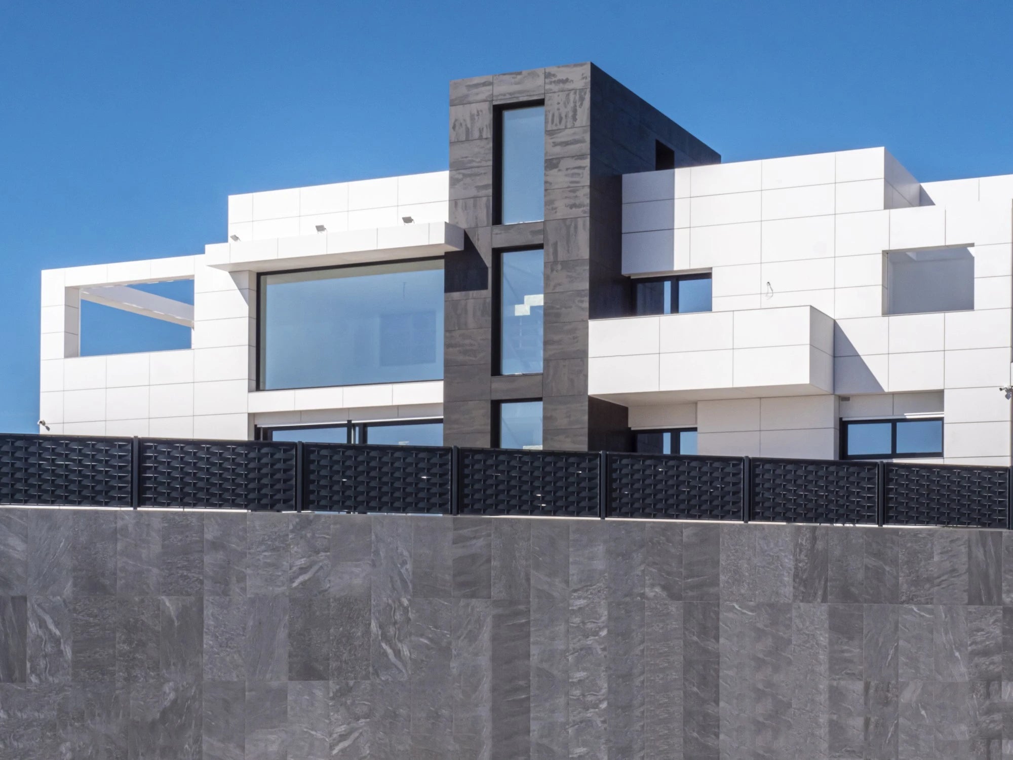 Dekton Uyuni exterior cladding with white geometric panels and gray stone accents — premium dekton surfaces fabricated and installed by Signature Stone LV