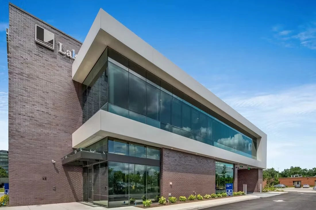 Dekton Zenith commercial building facade with white concrete and glass panels — premium dekton surfaces fabricated and installed by Signature Stone LV