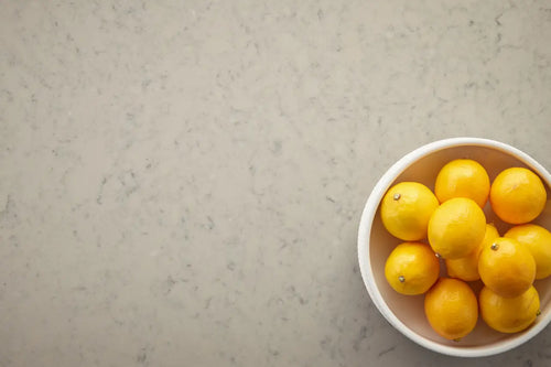 Fresh lemons in white bowl on marble surface with gray veining and polished finish — custom countertops fabricated and installed by Signature Stone LV