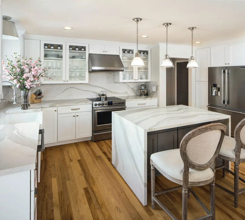 Brittanicca Warm quartz kitchen island and perimeter surfaces with white marble veining — elegant stone countertops installed by Signature Stone Las Vegas