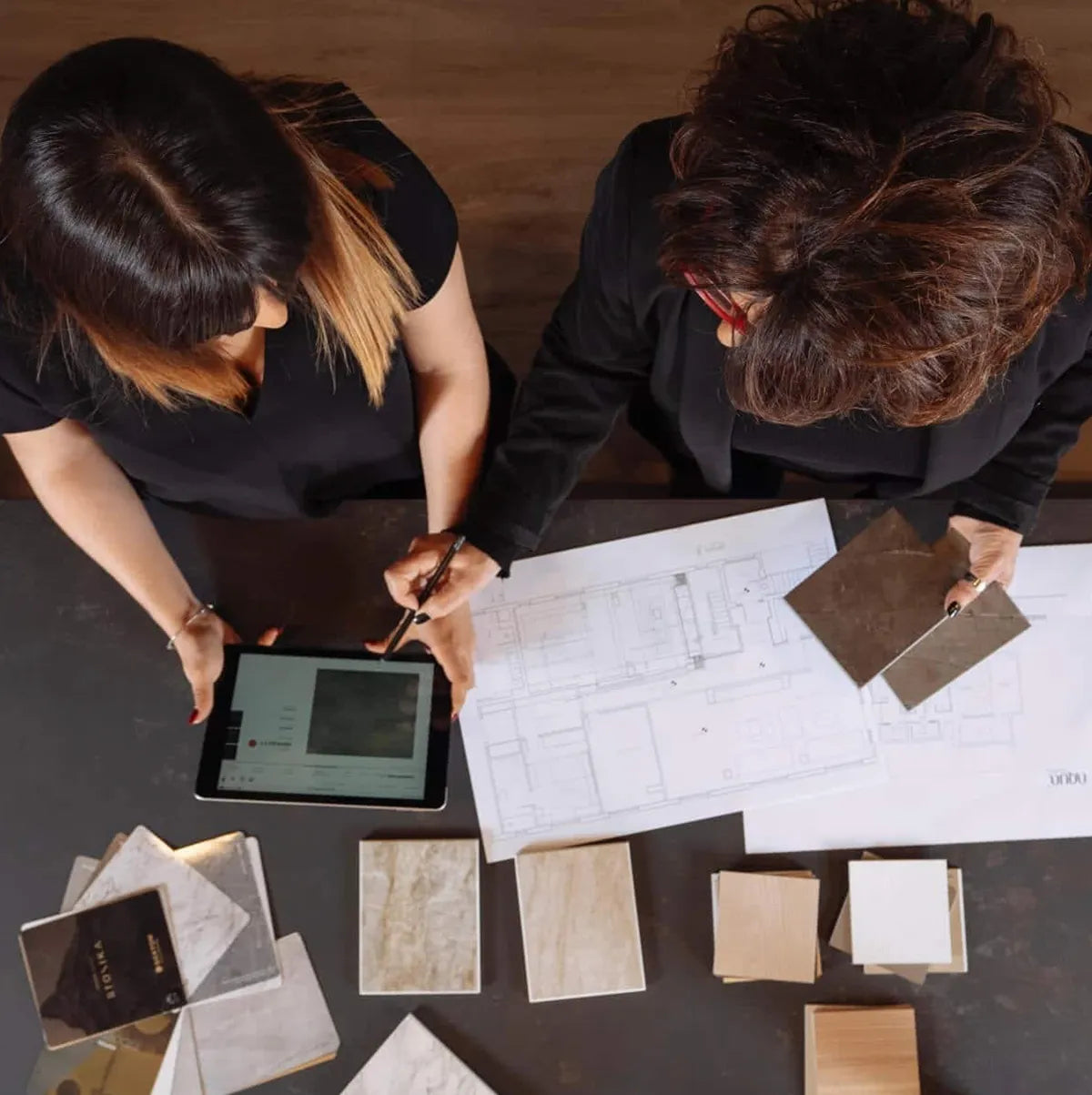 Countertop designers reviewing stone samples and blueprints for kitchen renovation.