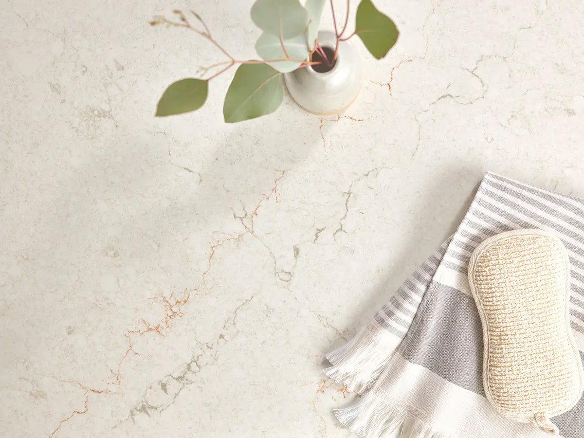 Marble surface with white background and gray veining alongside striped towel and natural elements — custom countertops fabricated and installed by Signature...