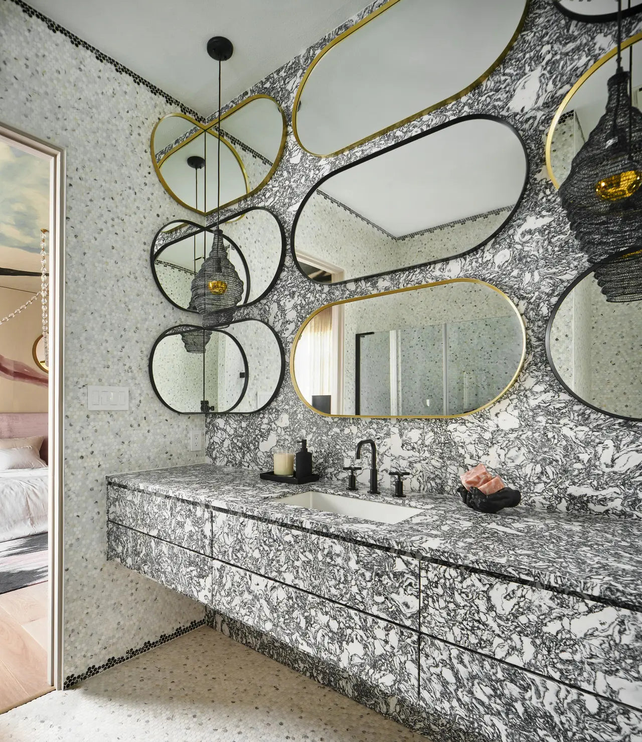 Marble vanity countertop with white and gray veining in modern bathroom featuring organic-shaped mirrors — expert countertop fabrication by Signature Stone L...