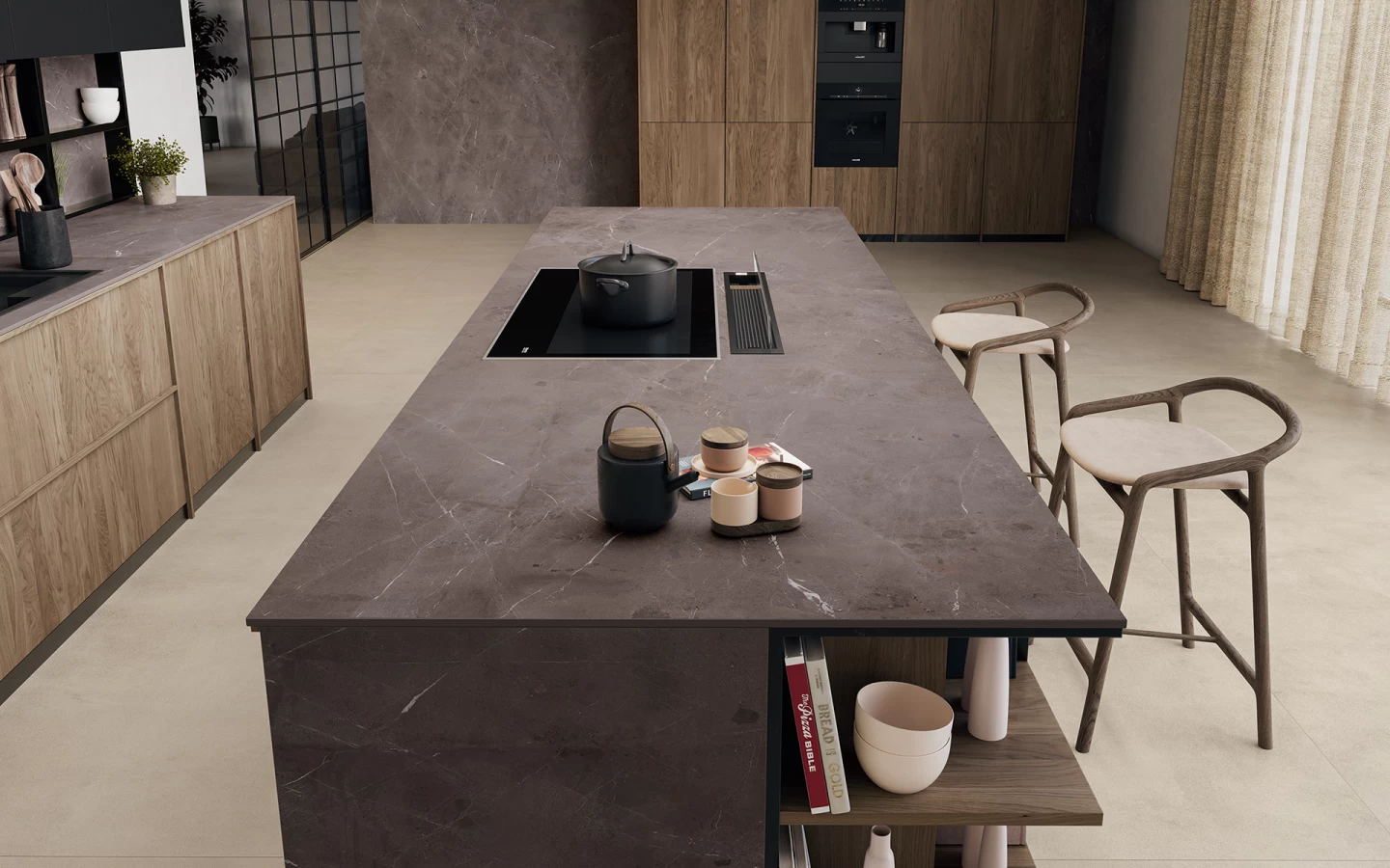 A modern kitchen with a large island featuring luxurious marble countertops, an induction cooktop, a pot, cups, and a teapot. Two wooden bar stools sit nearby, and shelves with decor and books are built into the island.